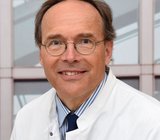 Porträtbild von Peter Hillemanns, der einen weißen Arztkittel trägt.