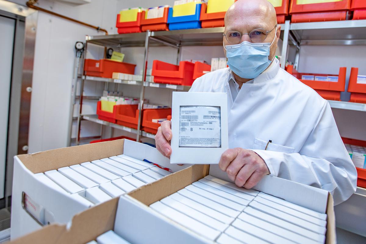 Professor Dr. Rainer Blasczyk im weißen Kittel hält ein kleines Päckchen mit Blutplasma in der Hand.  